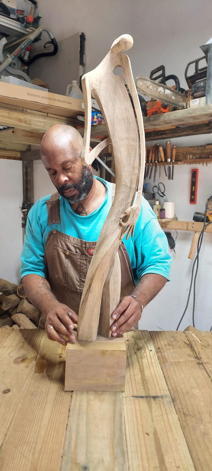 Eduardo Díaz Piñero ajustando una escultura de madera sobre su base en el taller
