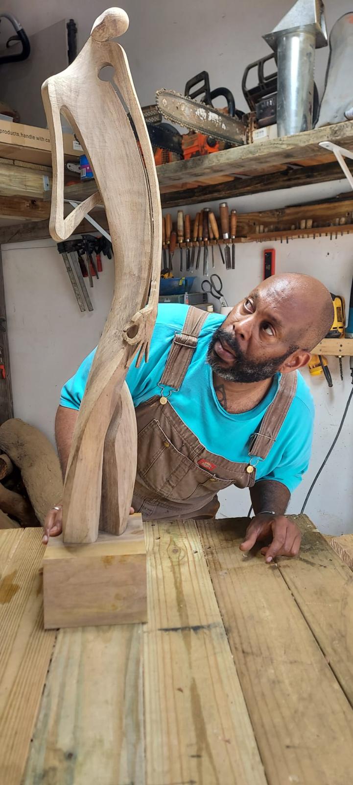 Díaz Piñero observando de cerca la escultura con herramientas de talla al fondo