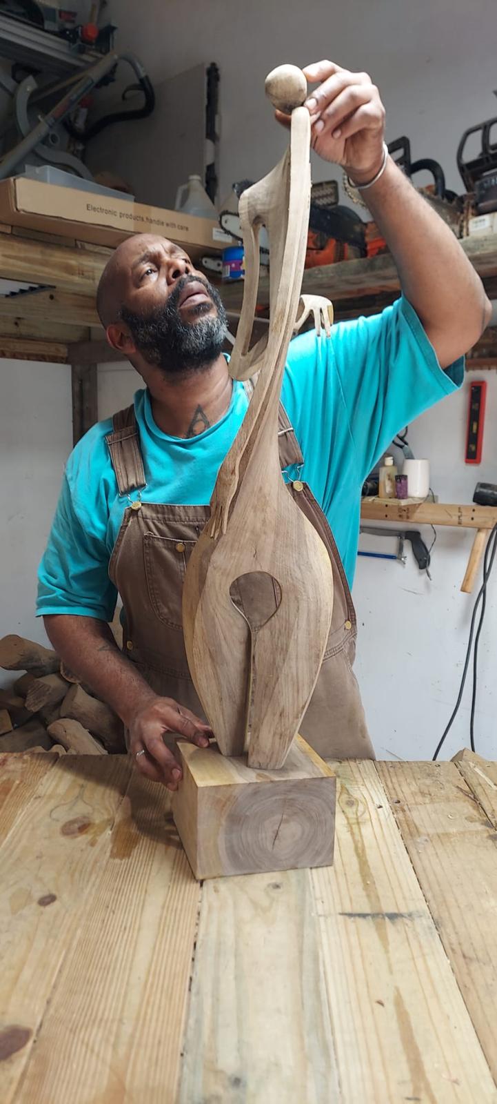 Eduardo Díaz Piñero alzando la mano hacia la cabeza tallada de la escultura
